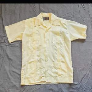 Vintage Guayabera kortärmad skjorta Storlek: S/M Den ena bröstfickans knapp saknas Och en av knapparna på ryggen är halv Axelmått: 43 cm Bröstmått: 53 cm Ärm: 22 cm Längd: 68 cm 