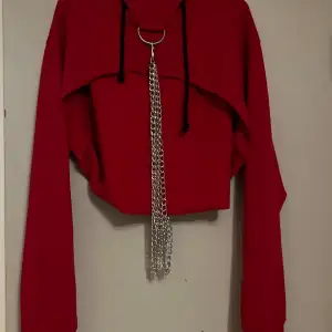Röd cropad hoodie med kedje detaljer, finns även hål för tummarna