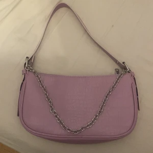 Handväska - Handväska köpt på h&m jag har använt den va 2 gånger den är i jätte fint skick o får plats med mycket den är ljus lila 