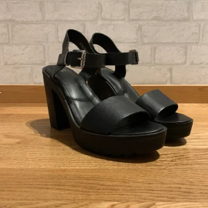 Svarta klackskor / sandaler  - Svarta snygga sandaler/klackskor, jättefina och trendiga, klacken är 11 cm. Har använts en gång i ca 1h men var för stora för mig men som man ser på bilden är de så gott som nya. Normal storlek.
