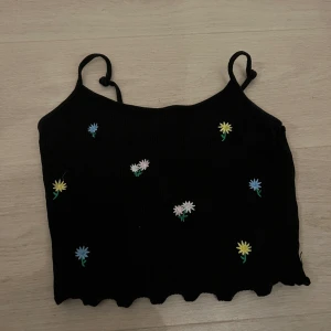 Linne - Det är ett svart linne som har små ferglada blommar på sig och den är jätte fin att ha på sommaren, jag har använt den typ 6 gånger och jag har knutit 2 knutar på banden men jag tror det går att få upp