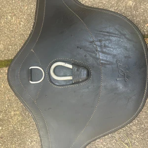 Svart magplatta från Lippo  - Säljer en svart magplatta från Lippo i skinn och flera D-ringar för enkel fastsättning av hjälptyglar. Bra skick men finns en del repor och hår. 110cm lång🥰Nypris 999kr