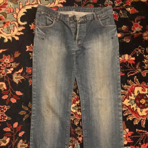 Blå jeans från Addict - Snygga blå jeans från Addict i klassisk femficksmodell. Jeansen har en rak passform med lätt slitning framtill och är tillverkade i 100% bomull. Perfekta för dig som gillar en enkel och tidlös stil.