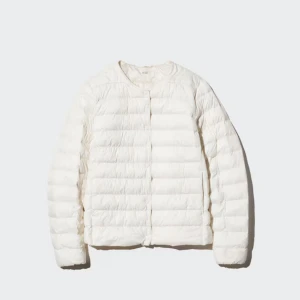 Vit dunjacka - Lätt och stilren vit dunjacka med rund halsringning och horisontella sömmar. Jackan är tunn, har lång ärm och stängs framtill med tryckknappar. Perfekt för lager-på-lager under kyliga dagar.