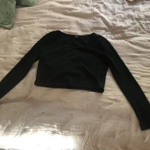 Svart croppad långärmad topp - En svart, croppad långärmad topp med rundad halsringning. Toppen är ribbad och har en slim passform har använt några få gånger lappen är bortklipps i tröjan storlek 148/156