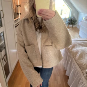 Beige teddyjacka med dragkedja - Mysig beige teddyjacka (bomberjacka) med oversized passform och stora fickor framtill. Jackan har lång ärm och stängs med dragkedja. Perfekt för dig som gillar en chill och trendig look. Materialet är fluffigt och ger en skön känsla under kyliga dagar. (Bilderna är från en annan säljare).