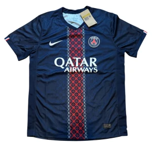 PSG matchtröja Nike marinblå röd - Paris Saint-Germain fotbollströja från Nike i marinblått med röd och vit rand längs mitten. PSG-logga på bröstet och Qatar Airways-tryck. Tillverkad i lätt och ventilerande polyester, perfekt för match eller träning.