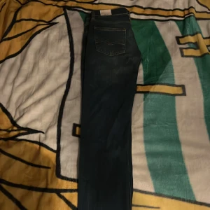 Mörkblå slim jeans från Replay - Snygga mörkblå jeans från Replay i modellen Zikry med slim fit. Klassisk femficksdesign, diskreta slitningar och kontrastsömmar. Perfekta för dig som gillar en smalare passform och stilren look.