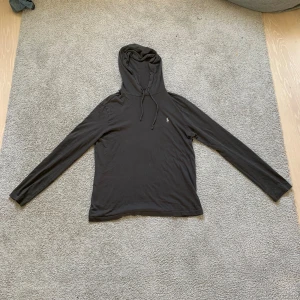 Svart hoodie från Polo Ralph Lauren - Svart hoodie från Polo Ralph Lauren med klassisk broderad logga på bröstet. Tröjan har huva med snörning och långa ärmar. Tillverkad i mjuk bomull som är skön mot huden. Perfekt för chill dagar och enkel att matcha med jeans eller joggers. Priset är inte skrivet i sten!