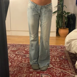 Ljusblå bootcut jeans - Snygga ljusblå bootcut jeans med låg midja. De har en klassisk femficksdesign och en avslappnad passform som ger en retro känsla. Perfekta för en casual look. (Bilden är tagen från förra säljaren och tjejen på bilden är 170)