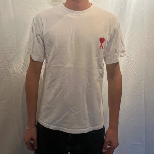 Vit t-shirt från Ami Paris - T-shirt från Ami Paris. Klassisk passform och rund halsringning. Tillverkad i mjuk bomull. Perfekt för en clean och stilren look. Modellen är 180cm