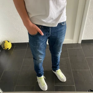 Dondup George - Snygga blå skinny jeans från dondup med klassisk femficksdesign och orangea sömmar. Jag är 185 och väger 77kg och de sitter bra på mig. Jeansen har en smal passform och är tillverkade i ett stretchigt denimtyg som sitter tajt längs benen. Perfekta för dig som gillar en modern och stilren look.