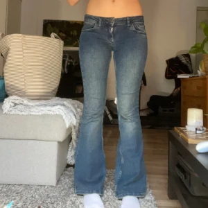 Lågmidjade mörkblå flare jeans  - Säljer ett par lågmidjade mörkblå flare jeans från Urban outfitters. De är tillverkade i mjukt denim och har knapp- och dragkedja framtill. Perfekta för dig som gillar enkel och stilren look. Storlek W27 L32