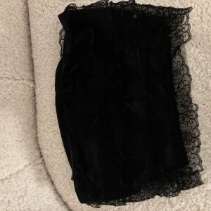 Svart kort topp med spetskant - Supersöt svart kort topp med transparent spetskant runt om. Toppen är tight och har spetsdetaljer. 