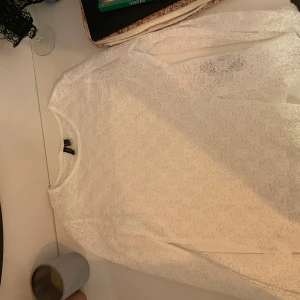 Vit spetstopp med lång ärm Vero Moda - Har en slit och breda ärmar