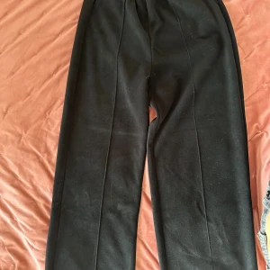 Svarta mjukisbyxor från Religion London - Svarta mjukisbyxor från Religion London med elastisk midja och bakficka med logotyp. Byxorna är i mjukt material och har en rak passform som ger en chill vibe. Perfekta för en avslappnad stil och enkla att matcha med hoodies eller t-shirts.