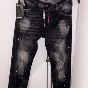 Svarta Dsquared2 Skater Jeans - Svarta jeans från Dsquared2 i modellen Skater Jean med coolt blekta partier och vita färgstänk. Klassisk femficksdesign, smal passform och dragkedja fram. Snygga detaljer och logotyp på bakfickan. Perfekta för dig som gillar streetstyle. Kontakta mig innan du köper !! 