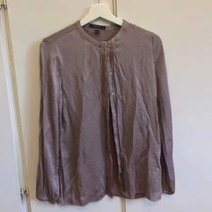 Ljuslila henley blus från Esprit - Säljer en stilren ljuslila henley blus från Esprit med rund halsringning och knappar framtill. Skjortan har långa ärmar och är tillverkad i ett mjukt, tunt material som känns skönt mot huden. Perfekt för dig som gillar en clean och enkel look.