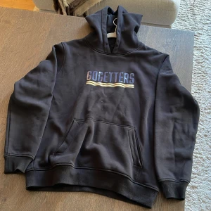 GOGETTERS Hoodie - Svart hoodie med stor huva och magficka. Gogetters tryck.
