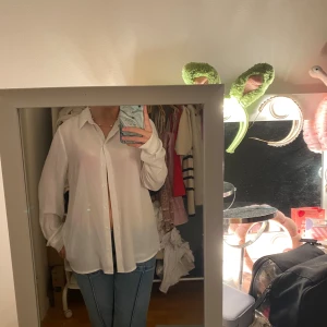 Vit oversized skjorta med knappar - Säljer en vit oversized skjorta med klassisk krage och knäppning framtill. Skjorta har långa ärmar och är tillverkad i ett tunt, lätt material som ger en avslappnad vibe. Perfekt att styla med jeans eller kjol för en clean look.