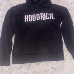 Svart hoodie från Hoodrich - Svart hoodie från Hoodrich med stor vit logga på bröstet och en luva, snöret har gått av från luvan. Det är strl S men passar Xs.