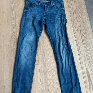 Slim Glenn jeans från Jack & Jones - Snygga blå jeans från Jack & Jones, modell Slim Glenn. Jeansen har en slim passform, klassisk femficksdesign och är tillverkade i mjukt denimtyg. Perfekt för dig som gillar en smalare siluett och stilren look.