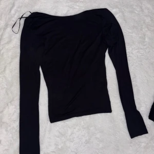 Svart långärmad topp med öppen rygg - Säljer en svart långärmad topp med smal passform och snygg öppen rygg. Perfekt för dig som gillar minimalistisk stil med en twist.