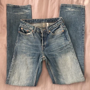 Weekday Straight Jeans  - Blå raka jeans från Weekday i modellen Pin Straight. Klassisk femficksdesign, mellanblå tvätt med snygga slitningar och kontrastsömmar. Lite färg längst ner på byxbenet har tvättats bort, inget som man tänker på! Storlek 24/32 som XS/S. Innebenslängd 80 cm, rakt över midjan 36 cm