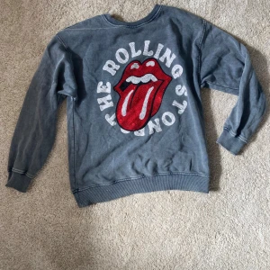 Grå Rolling Stones tröja från Zara - Cool grå sweatshirt från Zara med stort Rolling Stones-tryck på bröstet. Trycket har röda och vita små stenar som ger extra bling. Tröjan har rund hals, ribbade muddar och är långärmad. Jag säljer den nu för att den är för liten för mig❤️✨