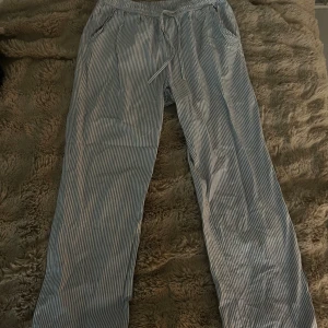 Randiga byxor från Lager 157 - Använda några gånger men som nya bara tvättade så går att strycka dom. Storlek S men passar även M. Luftiga byxor från Lager 157 i blåvitt randigt mönster. Modellen har resår och snörning i midjan samt raka ben. Perfekta för chill dagar eller när du vill ha en avslappnad look. Tillverkade i mjuk bomull för extra komfort. 🥰🥰