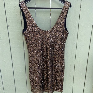 Glittrig paljettklänning i guld st.M-L - Supersnygg kort klänning täckt av guldiga paljetter med djup rundringning både fram och bak. Ärmlös modell som sitter tight och ger en riktigt festlig look. Perfekt för dig som vill sticka ut och glänsa hela kvällen.det står L på den men passar även M . Hämtas i norsborg botkyrka.