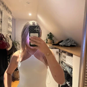 Vit ribbad body från Zara - Supersnygg vit ribbad body  från Zara med tunna axelband och halterneck. och har en tight passform som framhäver figuren. Perfekt för sommarens varma dagar och har en stilren, minimalistisk look.