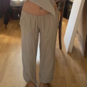 Beiga loose linnebyxor med snörning - Säljer ett par beiga linnebyxor med avslappnad passform och snörning i midjan. Byxorna har raka ben och är perfekta för en chill och bekväm stil. Lätta och luftiga, passar grymt till sommaren.