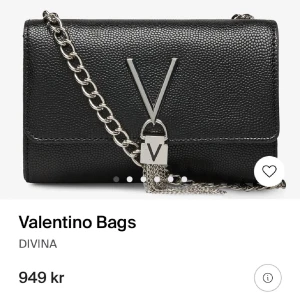 Svart valentino väska  - Snygg svart axelväska från Valentino med kedjerem i silver och ett stort V i metall framtill. Väskan är i präglat skinn och har en stilren, boxig form. Perfekt för dig som vill ha en statementväska med lyxig känsla och coola detaljer. Det går även att ha den som en kuvertväska. B 17 x H 11.5 x D 4 cm. Längd på rem: 17cm. Fri frakt kan jag lösa. 