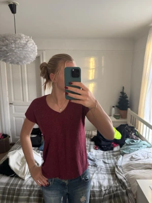 Vinröd t-shirt från Sister S - Vinröd t-shirt från Sister S i storlek S. T-shirten har v-ringning och korta ärmar, med en melerad look som ger en avslappnad vibe. Perfekt till jeans eller shorts för en chill stil.