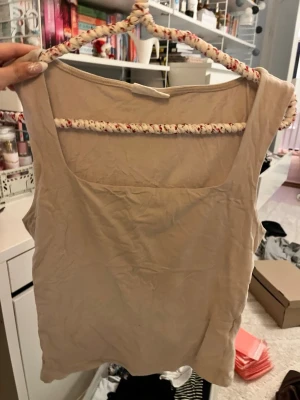 Beige linnetopp med fyrkantig hals - Säljer en enkel och stilren beige linnetopp med fyrkantig halsringning. Toppen är ärmlös och har en rak passform som gör den lätt att matcha med olika outfits. Materialet känns mjukt och lätt, perfekt för varmare dagar.