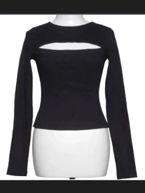 Svart långärmad topp med cut out - Säljer en svart långärmad topp med en snygg cut out-detalj över bröstet. Toppen har en figurnära passform och rund halsringning. Perfekt att styla med höga jeans eller kjol för en trendig look. Storlek M men passar för både S och M