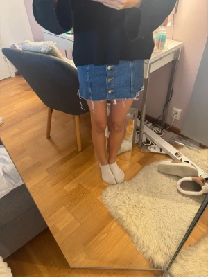 Blå jeanskjol med knappar från Ginatricot - Säljer en blå jeanskjol från Gina i storlek 34. Kjolen är kort, har en rak passform och snygga silverfärgade knappar framtill. 