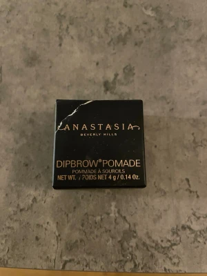 Anastasia Dipbrow Pomade Soft Brown - Dipbrow Pomade från Anastasia Beverly Hills i färgen Soft Brown. Kommer i en liten rund glasburk med svart lock och guldlogga. Perfekt sopig formula för att forma och fylla i brynen med en naturlig brun ton. Den är helt ny, bara kartongen som har gått sönder lite 
