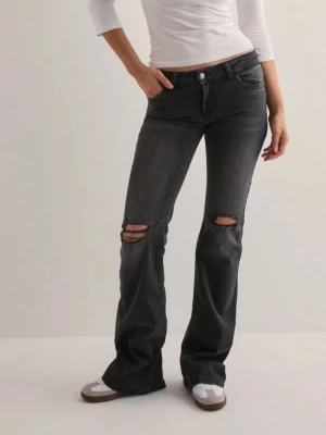 Bootcut svarta jeans med slitningar - Svarta bootcut jeans med slitna hål på knäna och klassisk femficksdesign. Jeansen har låg midja och är tillverkade i jeansmaterial med en mörk tvätt. Snygga detaljer på bakfickorna och breda benslut som ger en cool siluett. Lite slitna nere vid foten annars superfint skick!