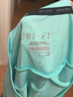 FC Barcelona Nike fotbollströja S - Säljer en FC Barcelona fotbollströja från Nike i ljusblå Dri-Fit polyester med mörkblå och gula detaljer på ärmarna. Tröjan har klubbmärke och Qatar Airways-tryck på bröstet, samt Nike-logga. Perfekt för dig som älskar Barca och vill ha en snygg matchtröja. Dock är texten inne i tröjan borta eftersom lotsnat. 