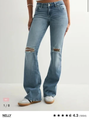 Nelly Low Waist Perfect Bootcut Jeans -  Helt oanvända nya bootcut jeans i ljusblå tvätt från Nelly, med slitningar vid knäna och snygga kedjedetaljer på bakfickorna. Jeansen är lågmidjade