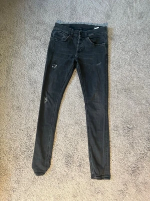 Svarta skinny jeans med slitningar - Snygga svarta skinny jeans med slitna detaljer på benen. Jeansen har klassisk femficksdesign och smal passform som sitter tight längs benen. Perfekta för dig som gillar en cool och avslappnad stil. Materialet är jeans med stretch för extra komfort.