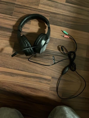 Kabelanslutet spelheadset med mikrofon - Bekvämt over-ear spelheadset med justerbar mikrofon och kabelanslutning via 3,5 mm kontakter. Passar perfekt för gaming och kommunikation. Skicket ser bra ut utan synligt slitage eller defekter. Lång kabel för flexibel användning vid dator eller konsol.