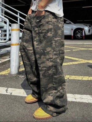 Baggy cargopants i camouflage - Säljer ett par riktigt baggy cargopants med camouflage-mönster. Byxorna har loose fit och breda ben för en avslappnad streetwear-look. Färgerna går i grönt, svart och grått. Perfekta för dig som gillar oversized stil och vill sticka ut.