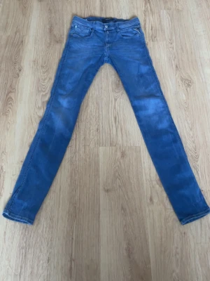 Blå Replay Anbass jeans herr - Säljer ett par blå Replay Anbass jeans med klassisk femficksdesign och snygg tvätt. Jeansen har normal passform och raka ben, tillverkade i mjukt bomullsmaterial med mycket stretch för extra komfort. Perfekta för dig som gillar stilrena och bekväma jeans.