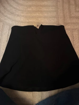 Svart tubtopp nelly  - Svart snygg tubtopp från Nelly. Bra material och skön att ha på sig. Åker inte ner som är vanligt att tubtoppar gör. Storlek S knappt använd. 