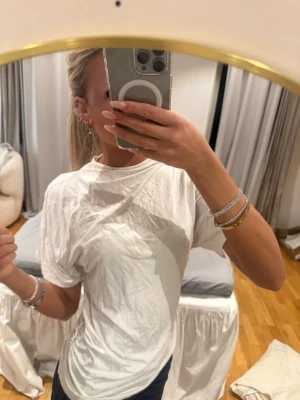 Vit basic t-shirt i bomull - Enkel vit t-shirt i mjuk bomull med rund hals och korta ärmar. Perfekt till jeans eller shorts för en clean och avslappnad look. Klassisk passform och stilren design utan tryck eller mönster.