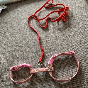 Sele, till kanin  - Ett kanin sele i rosa med hjärtan på. Det röda ingår också i priset och det är lite som är bitet på den men ändå i fint skick. Denna är alltså använd men i fint skick. (Till lite mindre kaniner eller så)