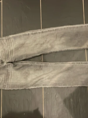 Gråa Levis 501 jeans straight fit - Säljer ett par gråa Levis 501 jeans med klassisk rak passform och femficksmodell. Jeansen har en snygg tvättad look och tydliga sömmar på bakfickorna. Etiketer borta men annars i fin form